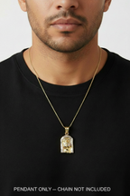A close-up of a man wearing a gold chain necklace with a clear acrylic pendant containing gold foil details, set against a plain light gray background.