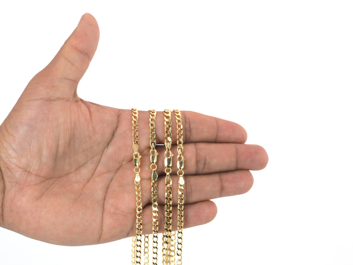 Three gold chains of different link styles draped over an open hand against a plain white background.