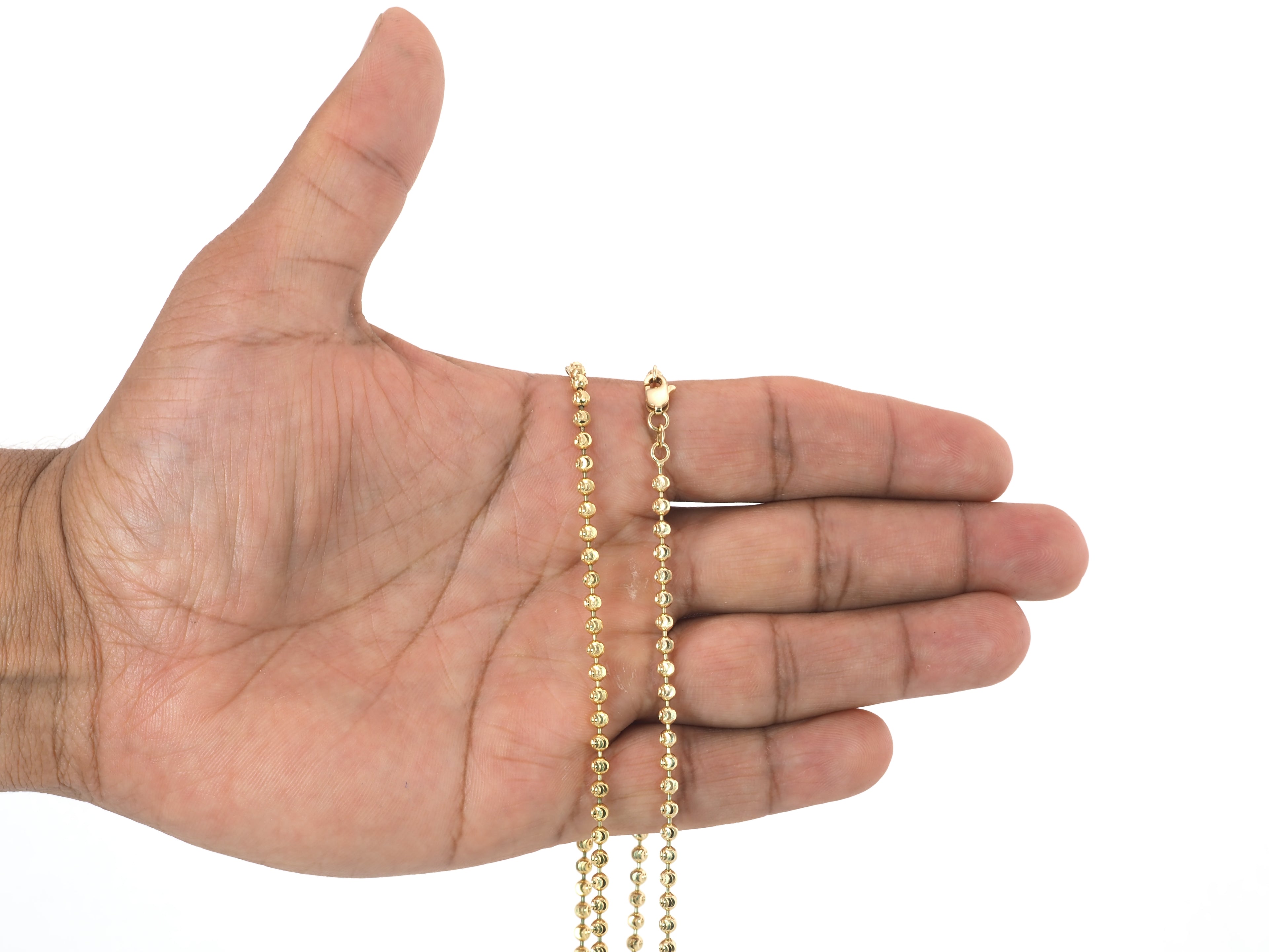 A gold ball chain necklace draped over an open hand against a plain white background.